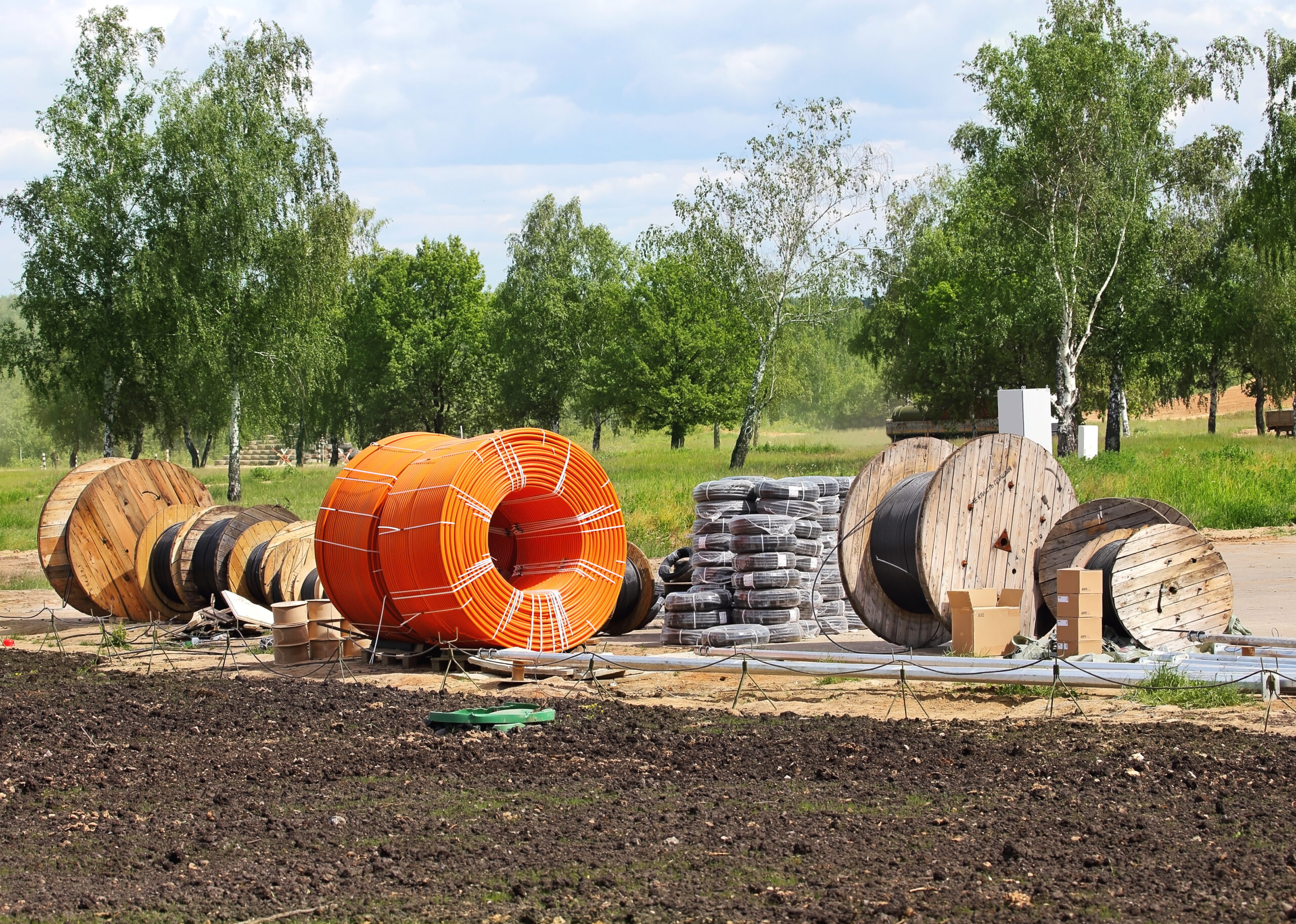Reels of cable and conduit prepped at a construction site for laying underground fiber network